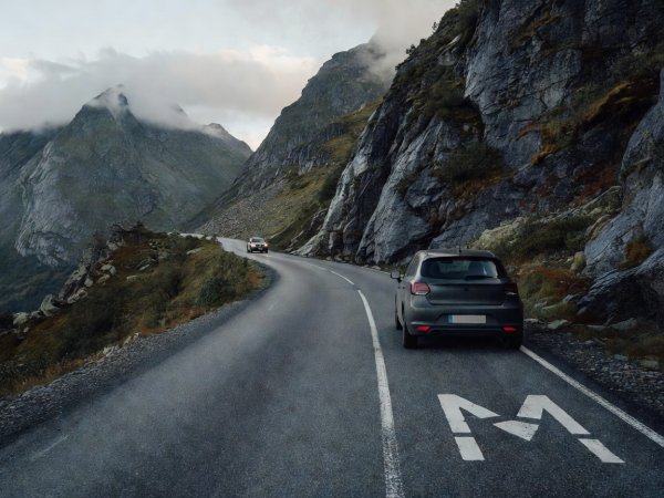 Hatchback paused inside a signed M passing bay on a narrow Norwegian mountain road to let oncoming traffic pass